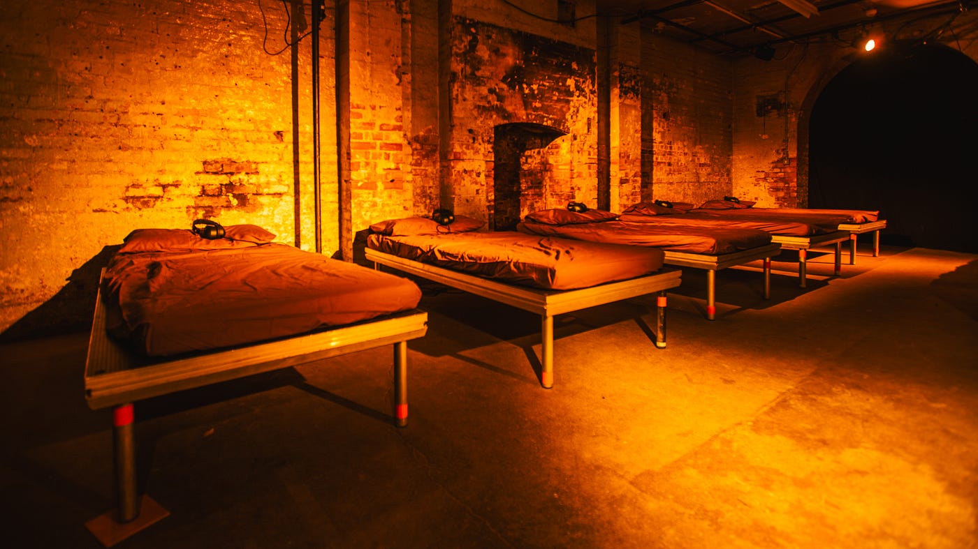 A row of spartan beds against a derelict brick wall
